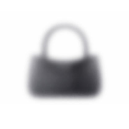 A dark-colored "Mystery bag" 3D-printed handbag with a short handle is seen against a white background. The image is blurry, making its details and texture unclear.