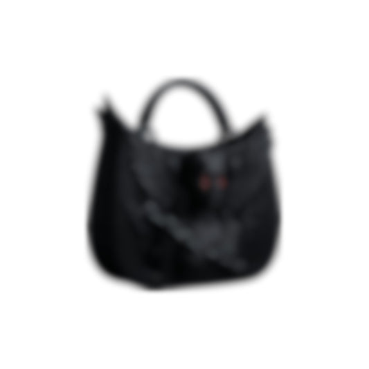 A blurred image shows the "I AM HERE" 3D-printed handbag with short handles against a white background. The sculptural details of the bag are not clearly visible due to the image's blurriness.